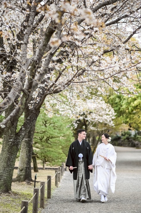 桜並木を歩く和装の新郎新婦